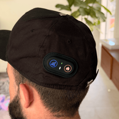 Back view of a man wearing the EliteRelief red light therapy cap, showing the control buttons on the rear of the cap