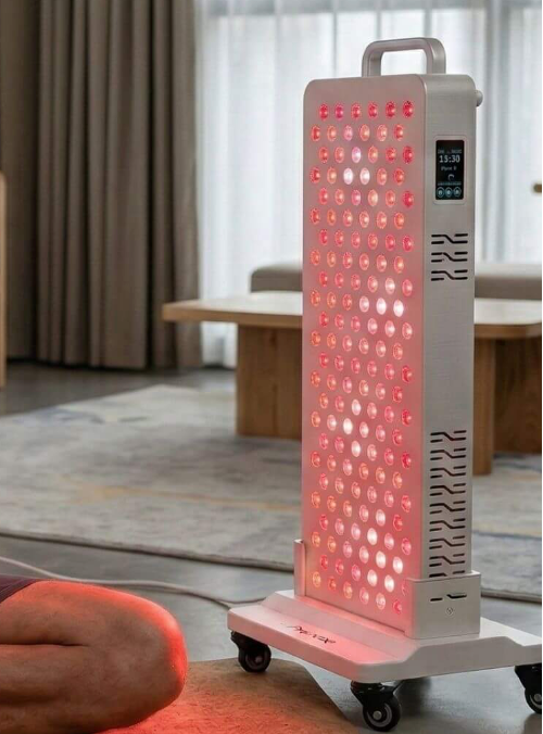 Portable LED light therapy device in a room setting with a person lying on the floor.